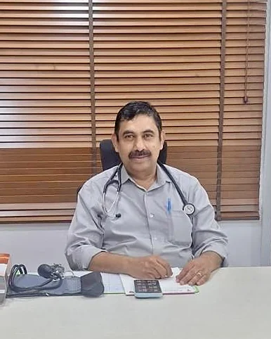Dr. Rangaraj R seated at his desk in the consultation room, wearing a stethoscope