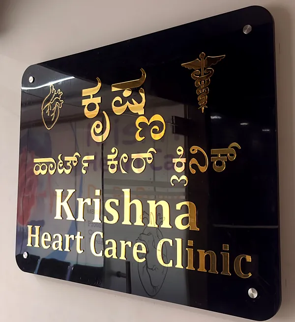 The clinic's black sign with gold lettering reading Krishna Heart Care Clinic, beside the glass entrance door